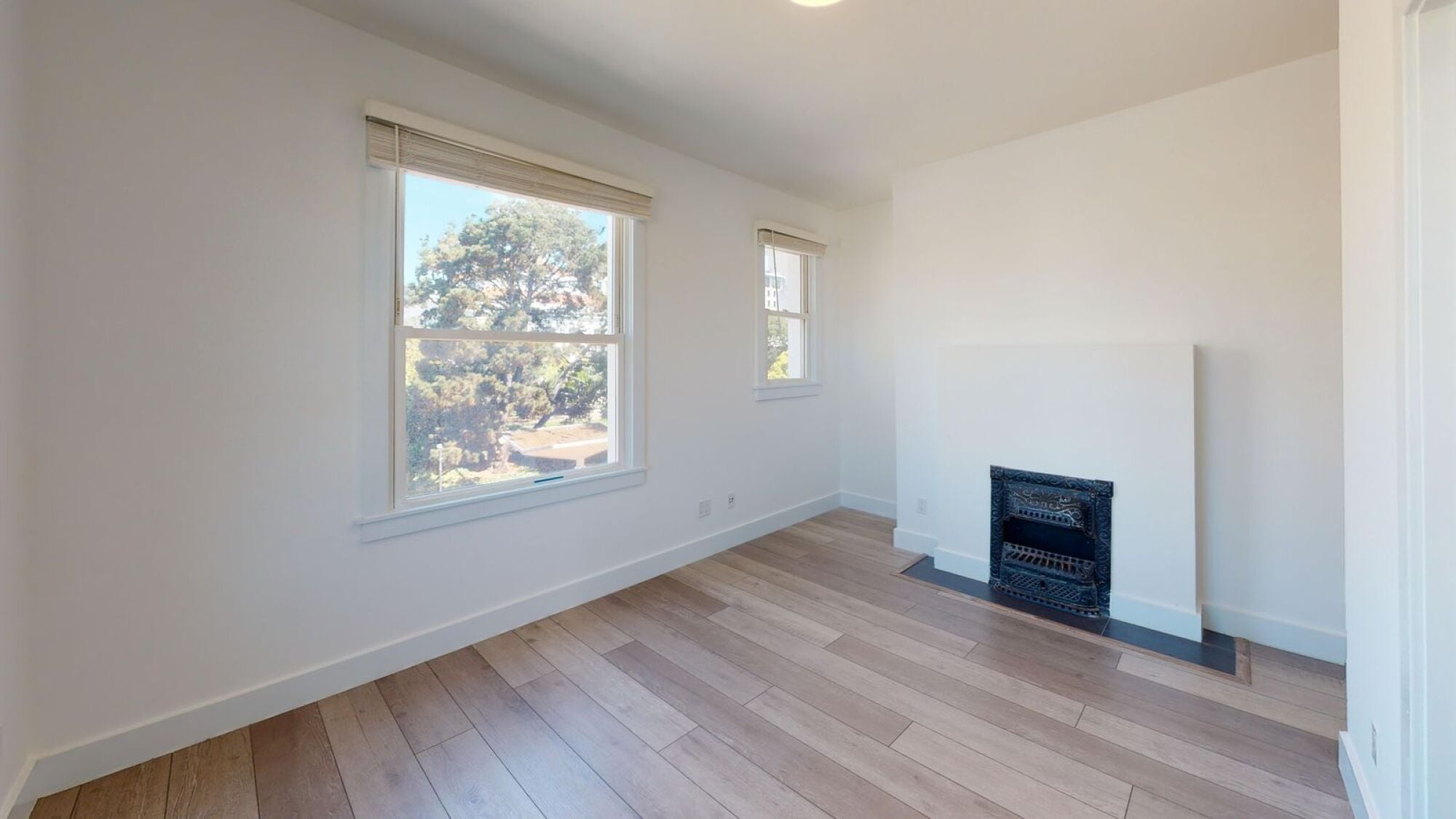 A room with a fireplace and a window showing trees outside.