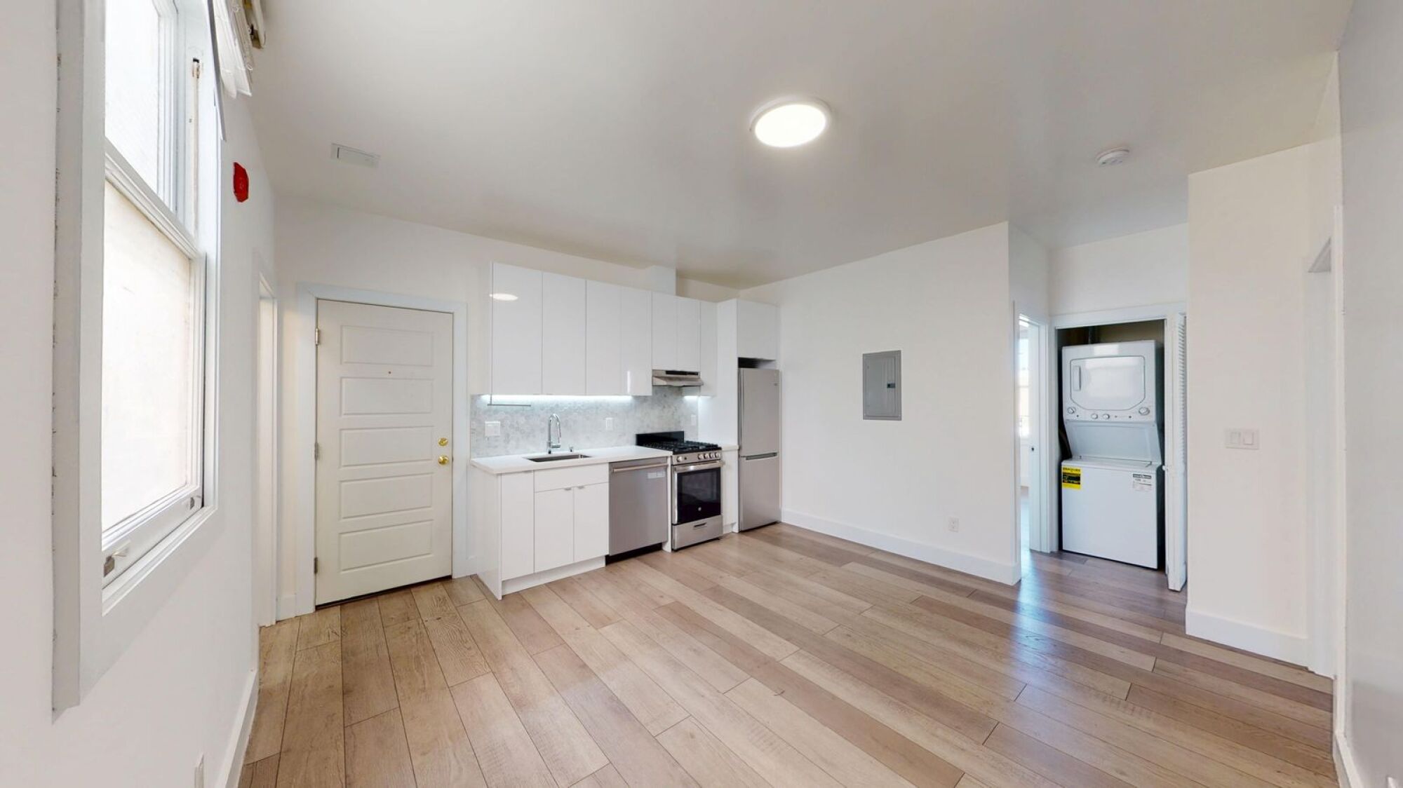 A kitchen with white cabinets and a wooden floor.