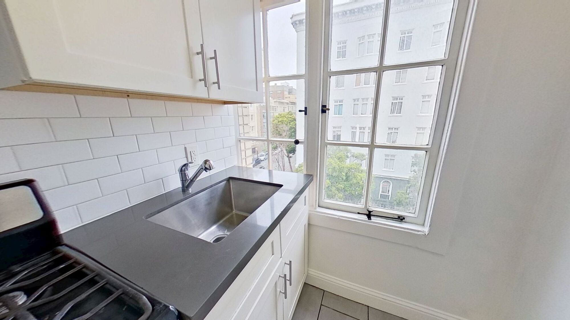 A kitchen with a black countertop and a window overlooking a building.