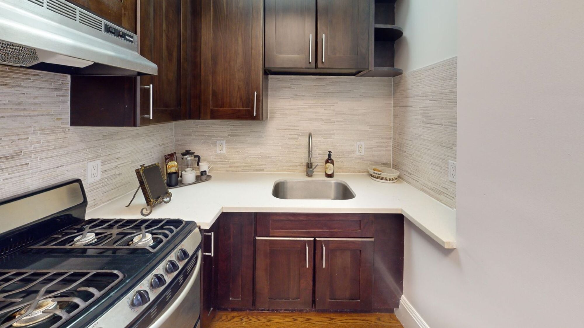 A kitchen with a stove, sink, and cabinets.
