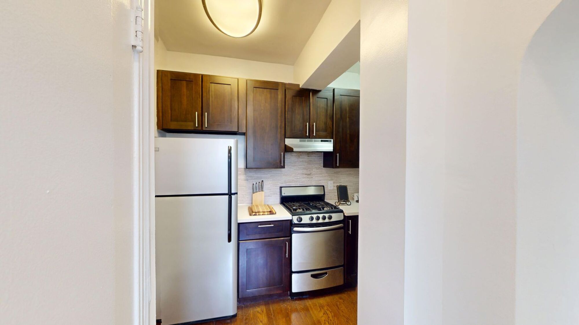 A kitchen with a refrigerator, stove, and cabinets.