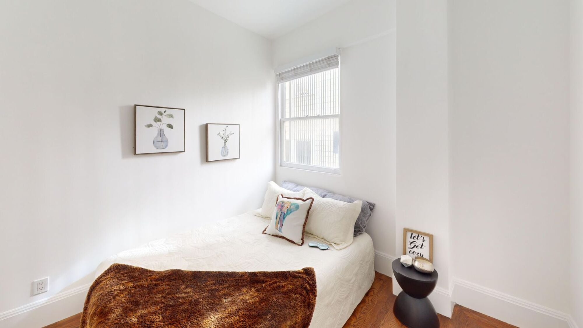 A bedroom with a bed, pillows, a rug, and pictures on the wall.