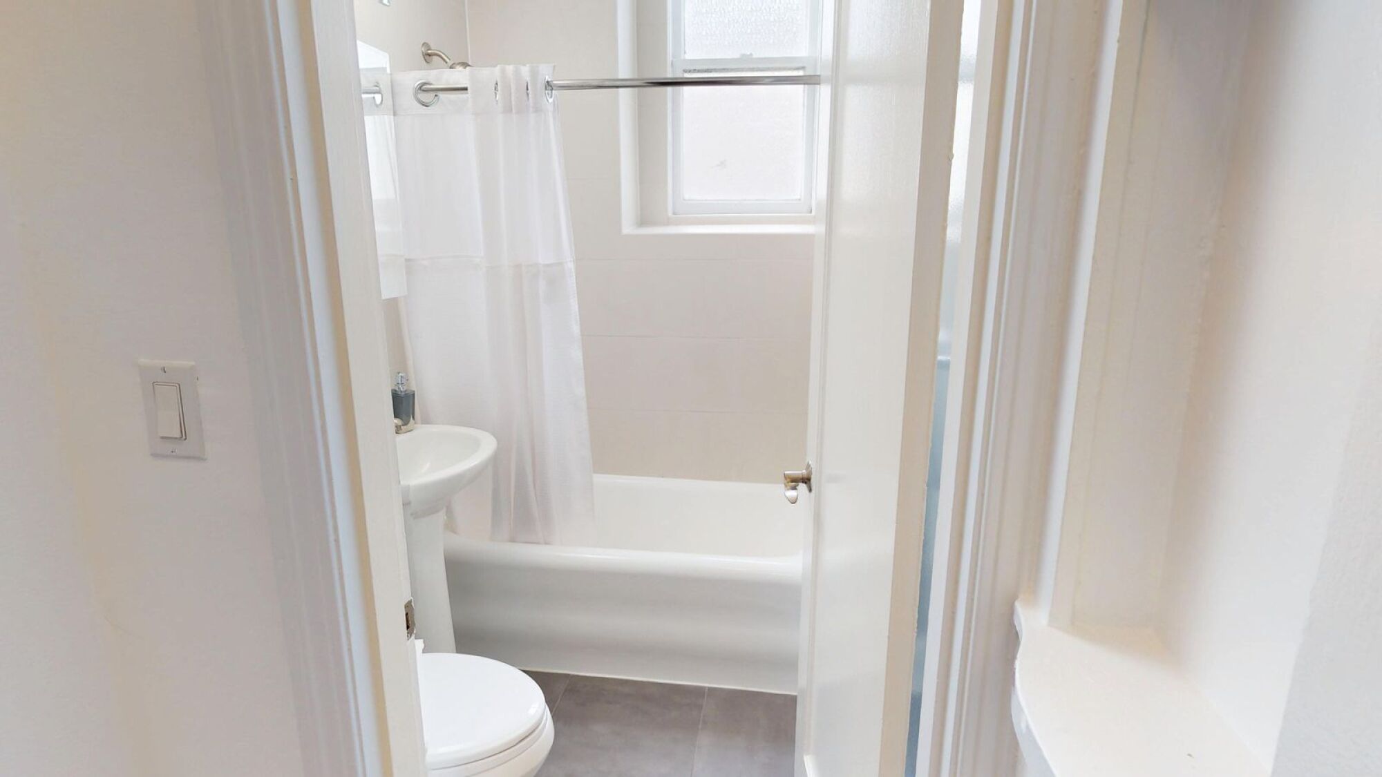 A white bathroom with a toilet, sink, and bathtub.