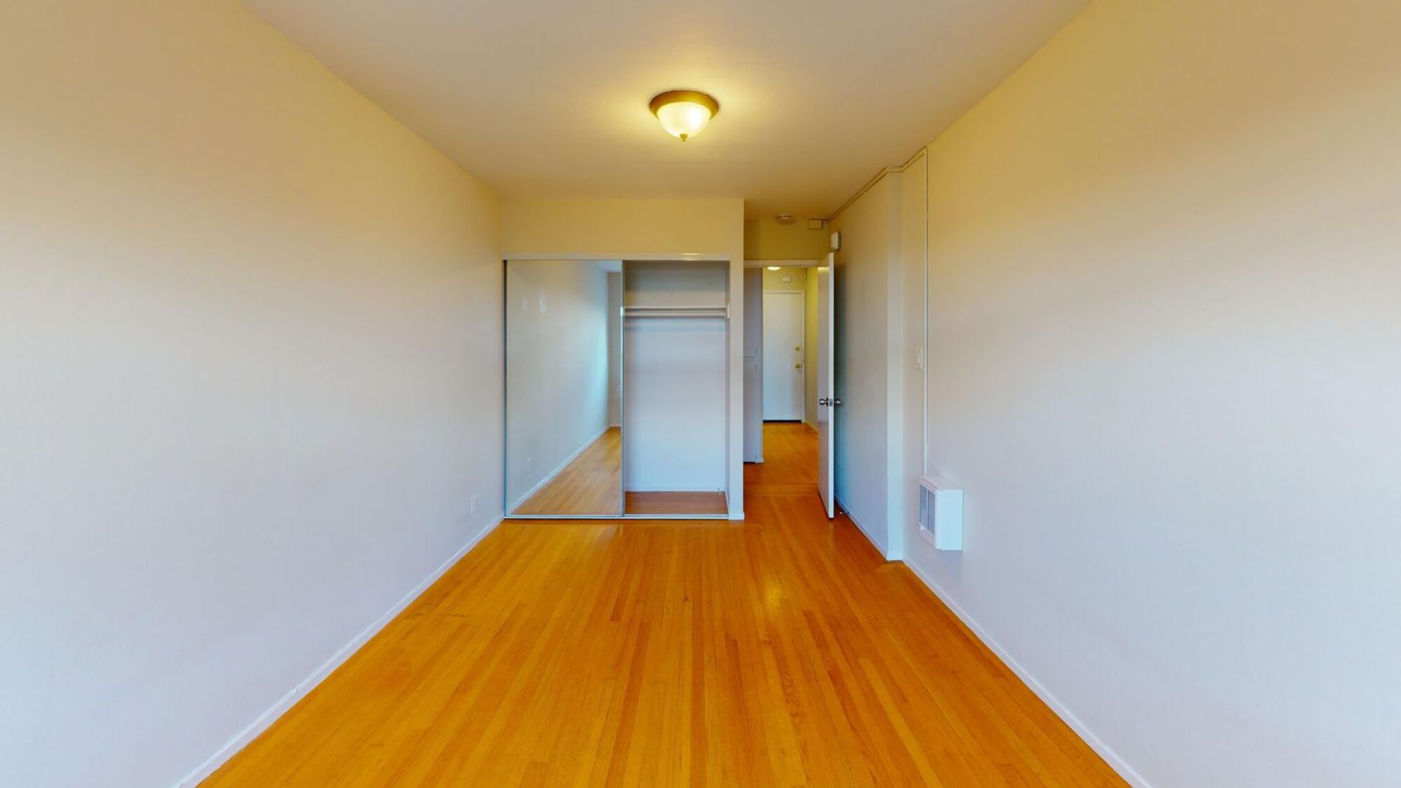 A long hallway with a wooden floor and white walls.