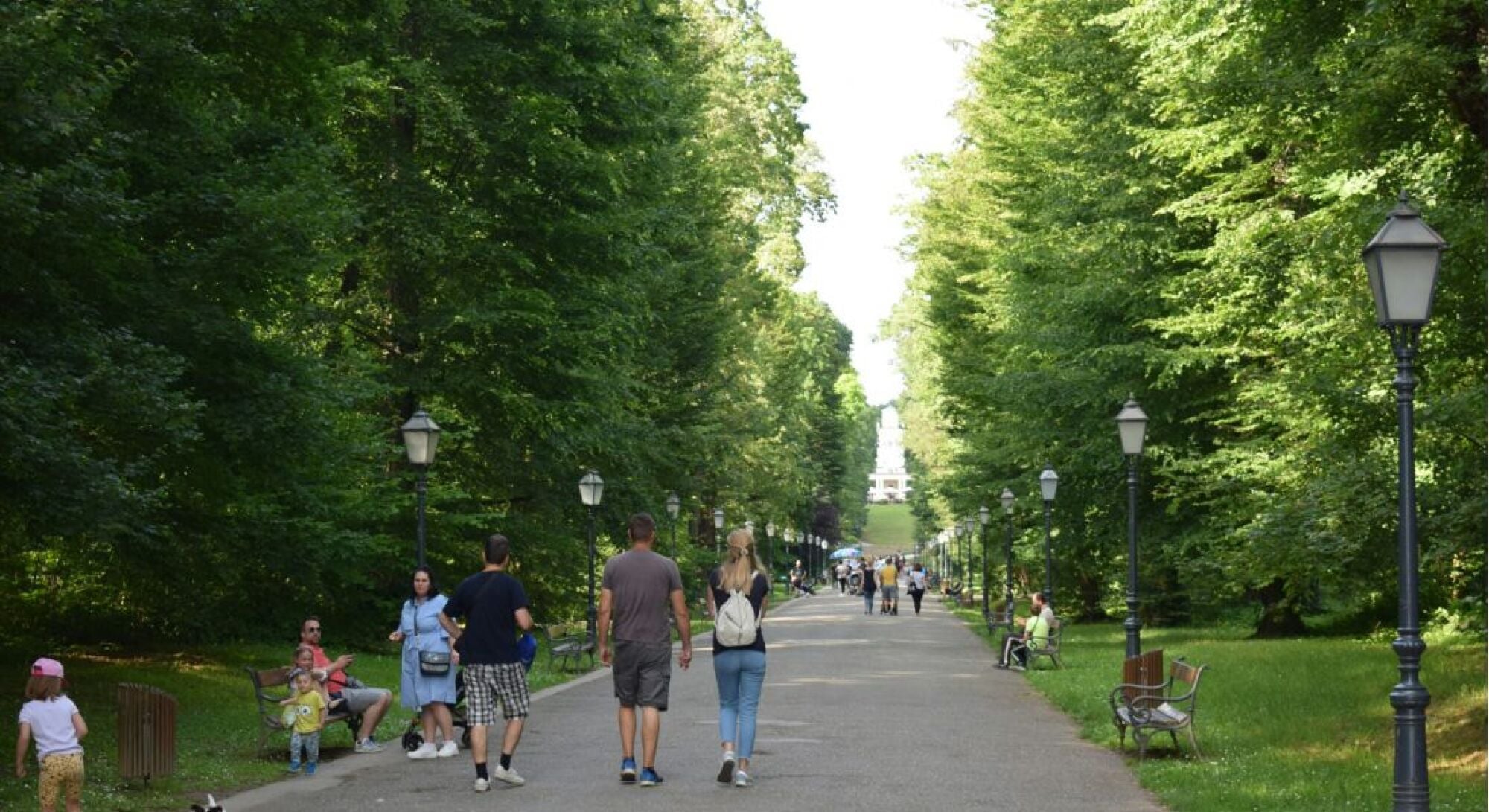 Middle aged woman walking a bike near a park