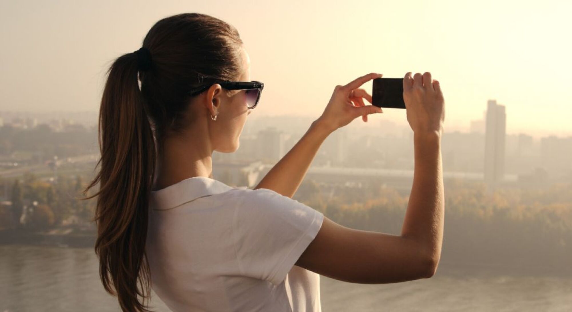 Sonder A woman photographing a city skyline, capturing the urban landscape with her camera.