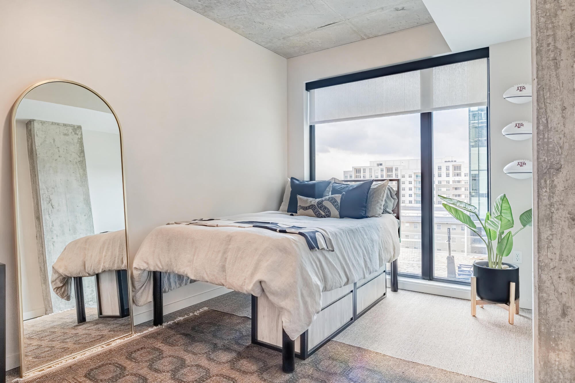 Furnished bedroom with floor-to-ceiling windows and city views at Rev student apartments in College Station, TX.