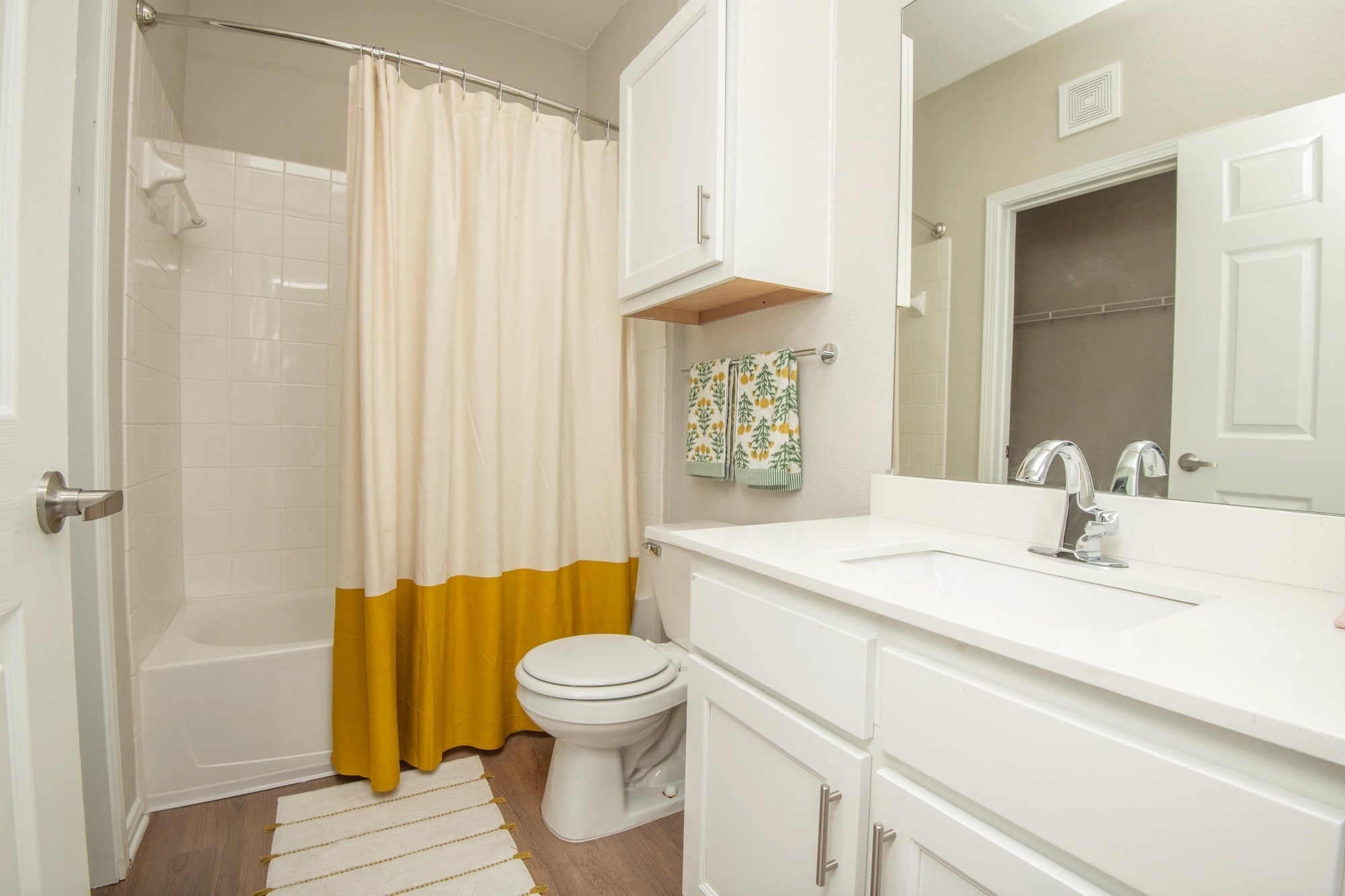 Apartment bathroom at The Heights with a vanity, shower-tub combination, and white cabinetry.