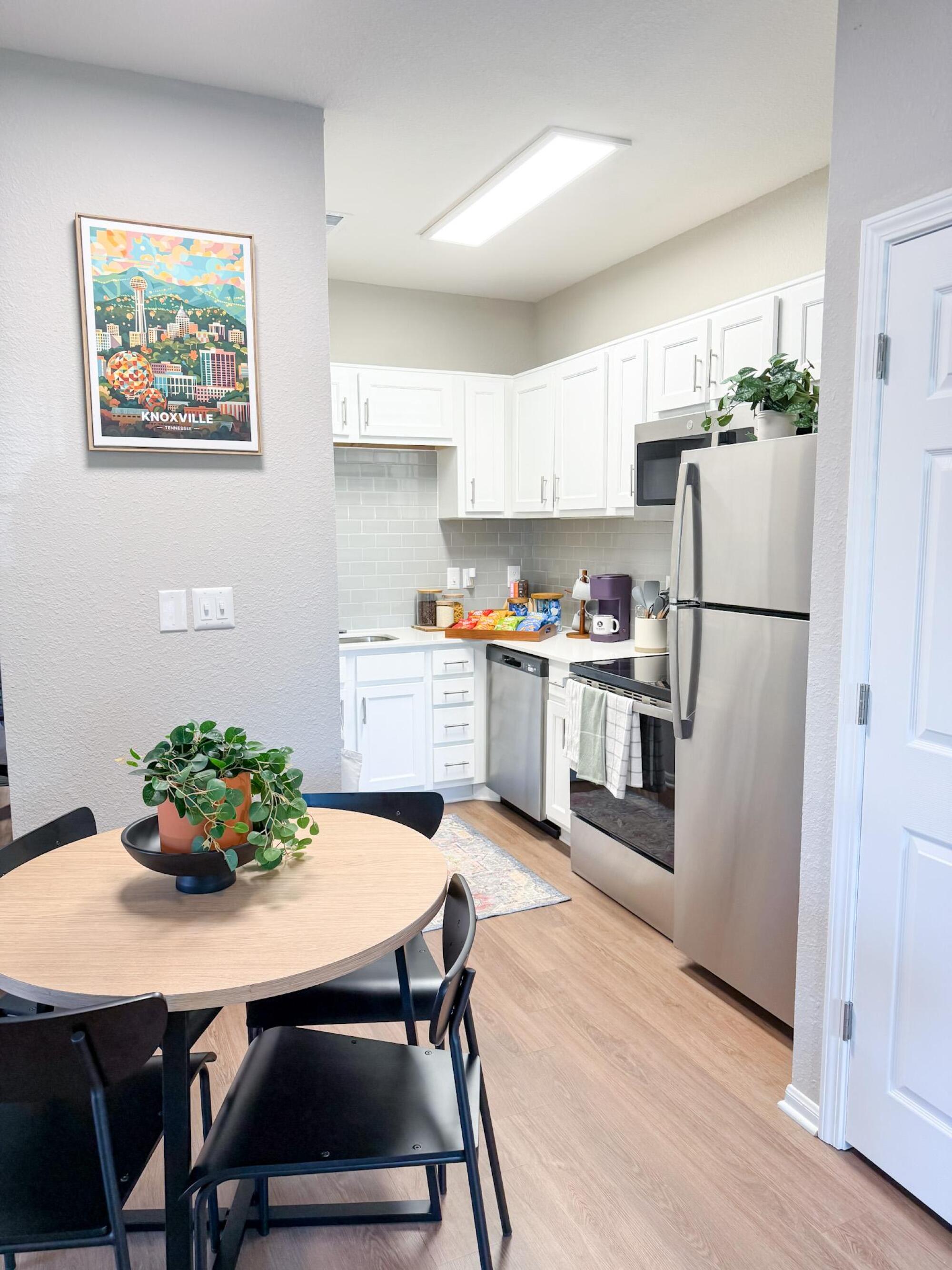 Apartment kitchen at The Heights with white cabinetry, stainless steel appliances, and a round dining table.
