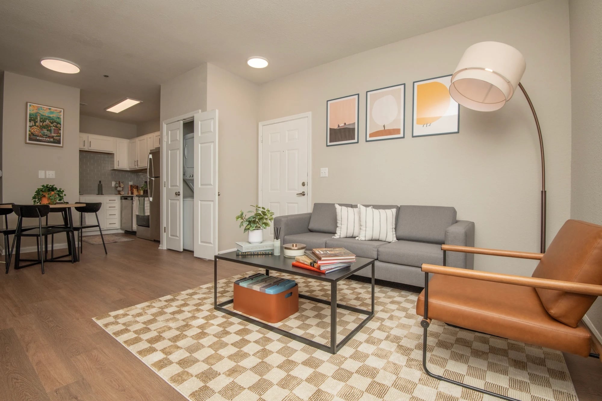 Furnished living room at The Heights with a gray sofa, dining area, and kitchen in the background.