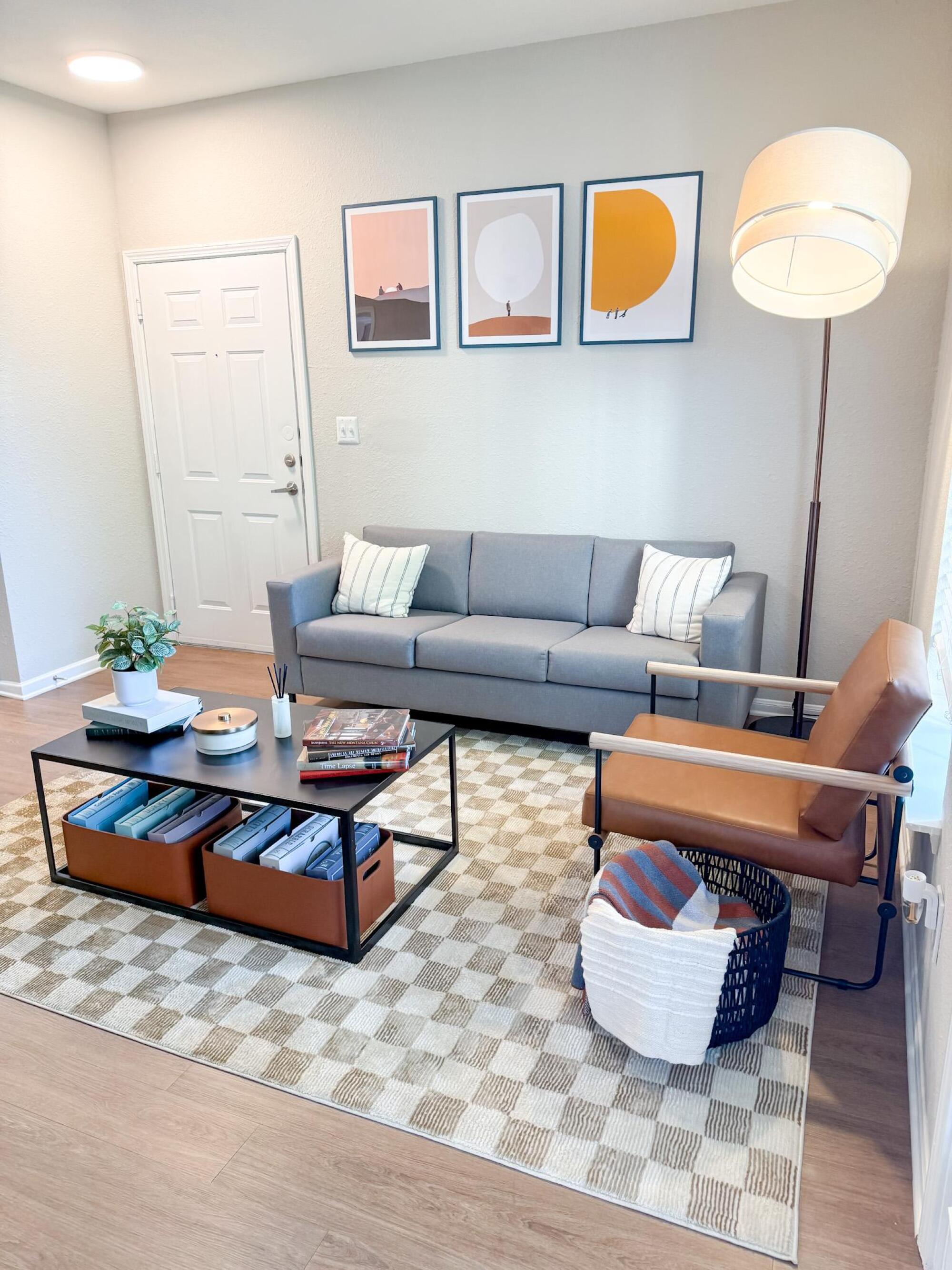 Bright furnished living room at The Heights with a gray sofa, leather chair, artwork, and coffee table.