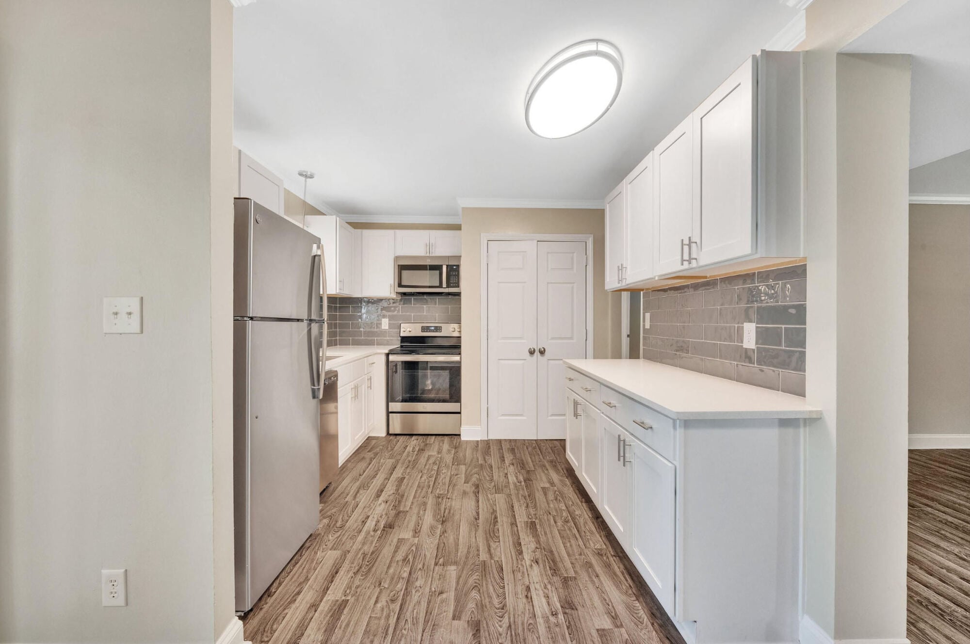 Renovated kitchen at Maple Run in Charlotte, NC with stainless steel appliances, white cabinets, and a gray subway tile backsplash.