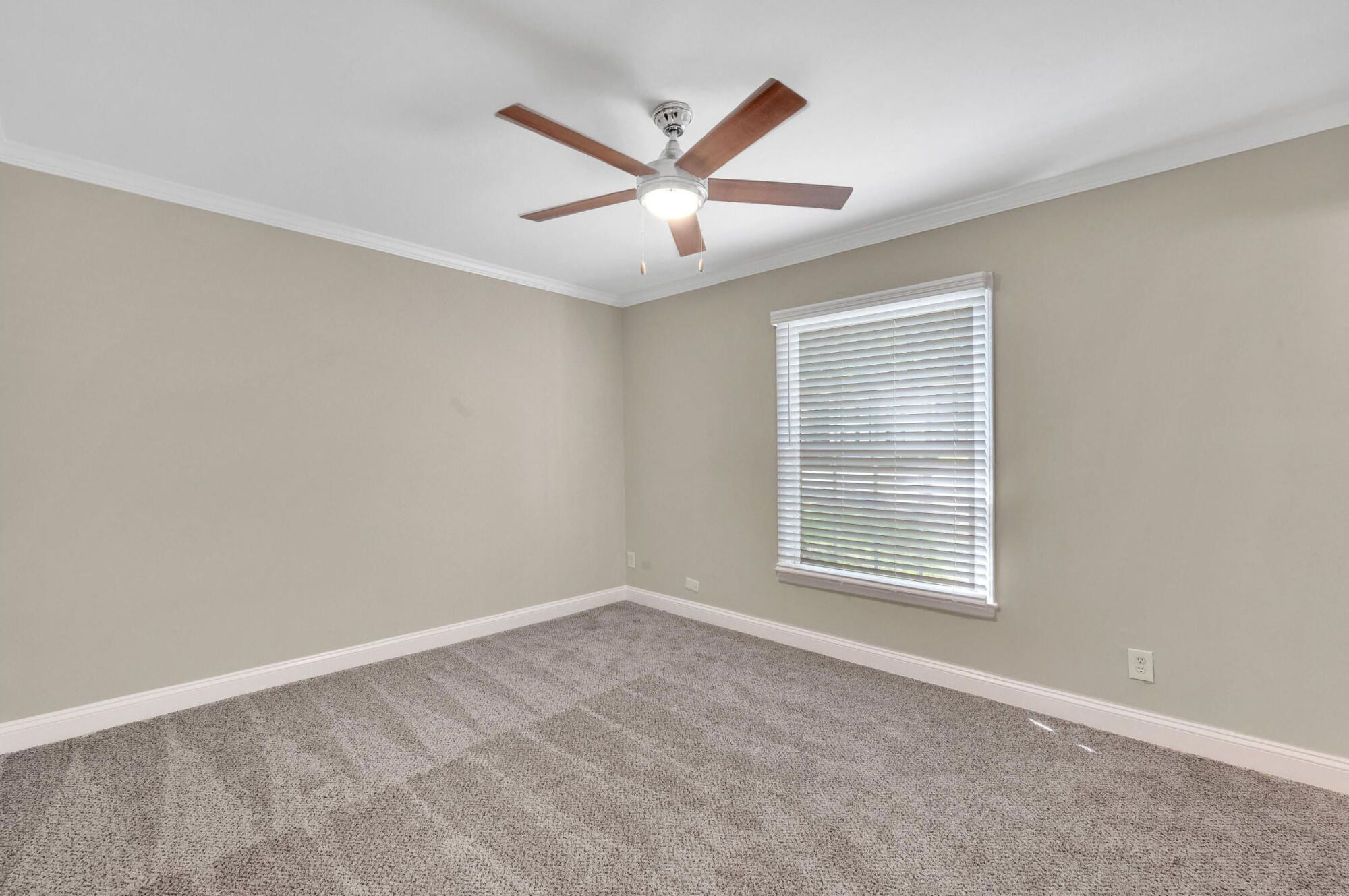Carpeted bedroom at Maple Run in Charlotte, NC with a modern ceiling fan and a bright, blinds-covered window.