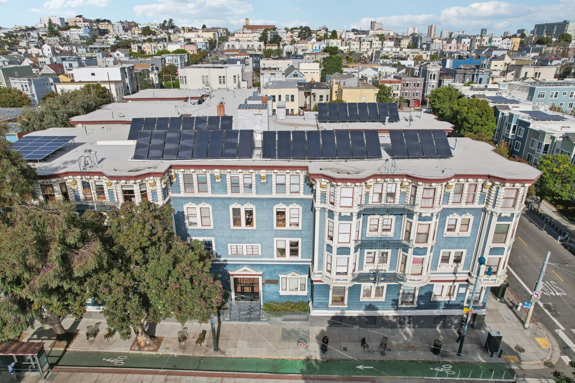 A building with solar panels on the roof is surrounded by a cityscape.