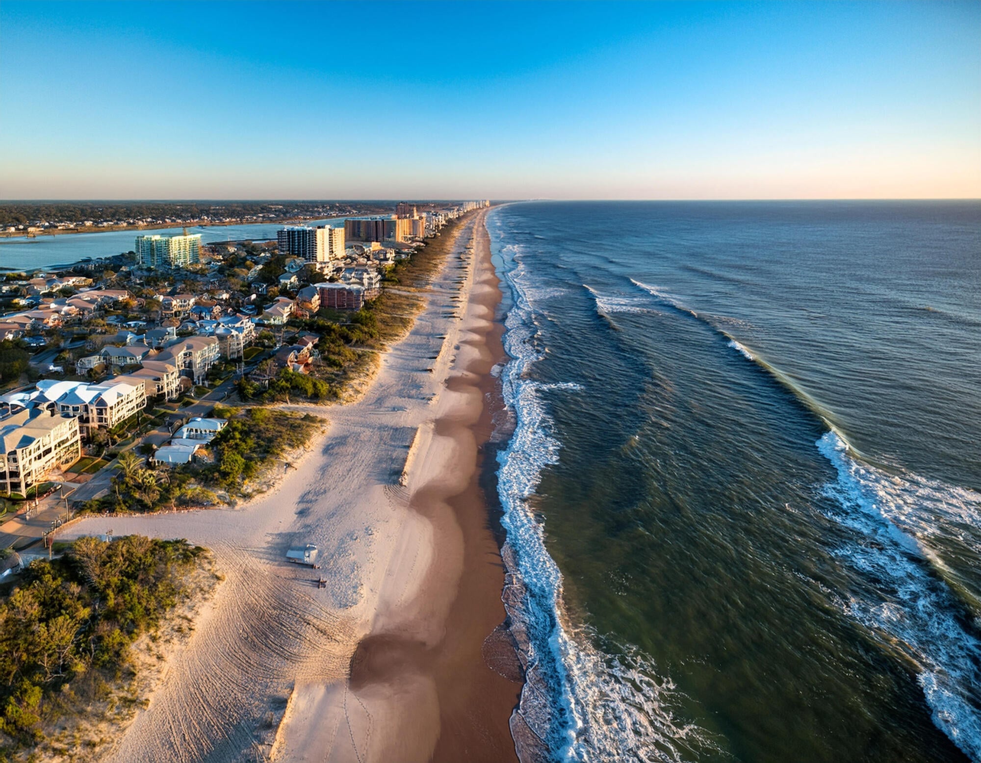 Aerial view of the Wilmington, NC coastline near The Sterling at Center Point, with sandy beaches, oceanfront homes, and rolling Atlantic surf.