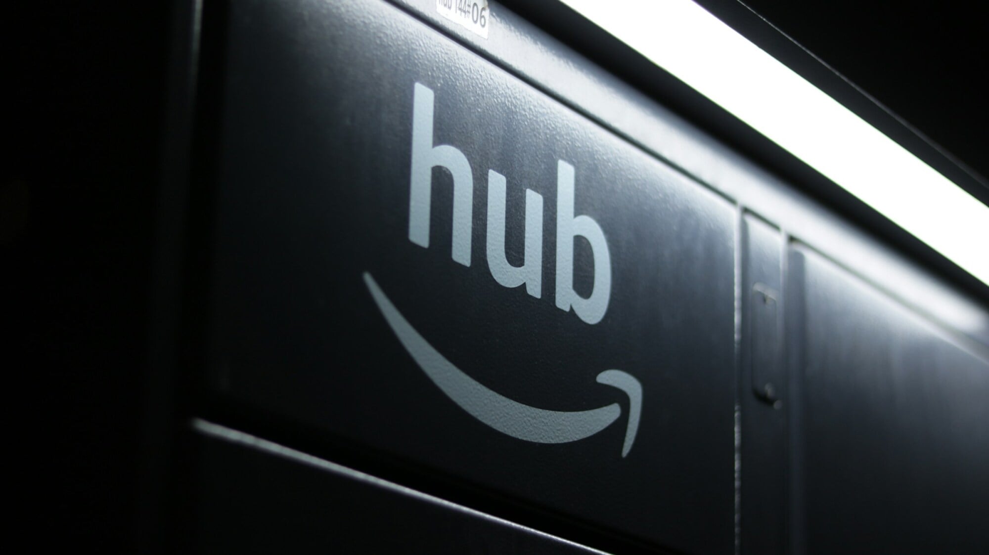 Close-up of an Amazon Hub locker with the Amazon logo and the word “hub” illuminated by an overhead light.