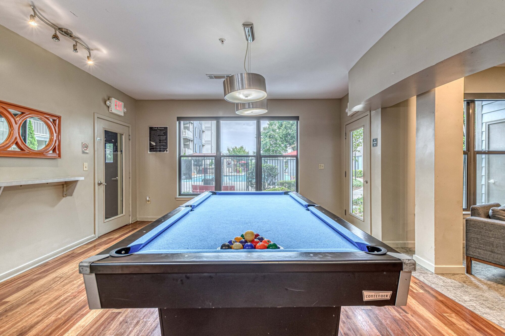 Game room with a blue pool table, foosball table, wood floors, and modern decor on the walls at Apex West Midtown.