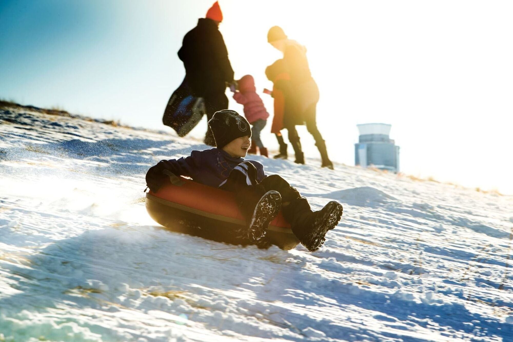 Child sledding down a snowy hill in an inner tube
