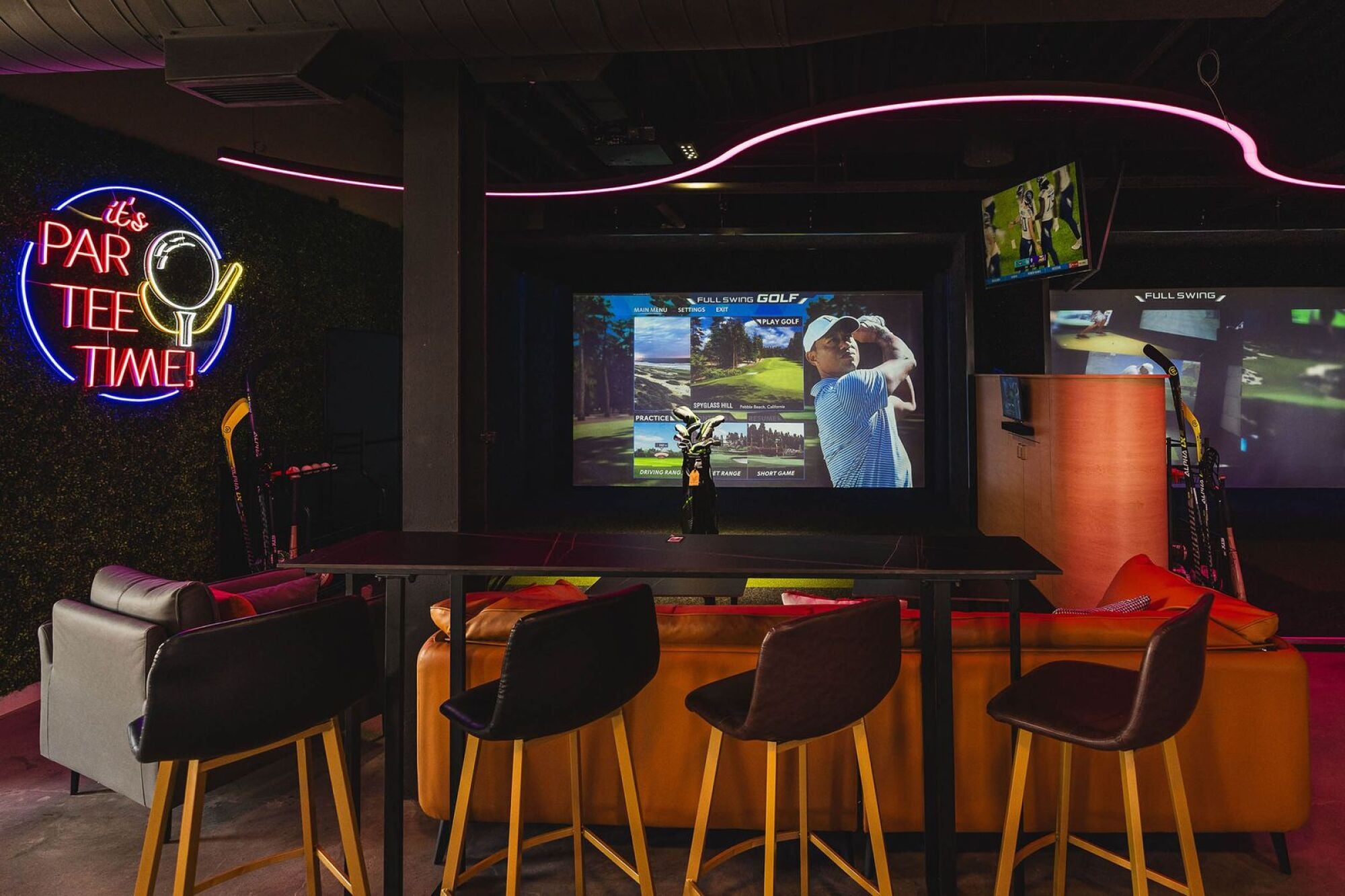 Sports suite featuring bar and chairs and large screen tv showing golf game