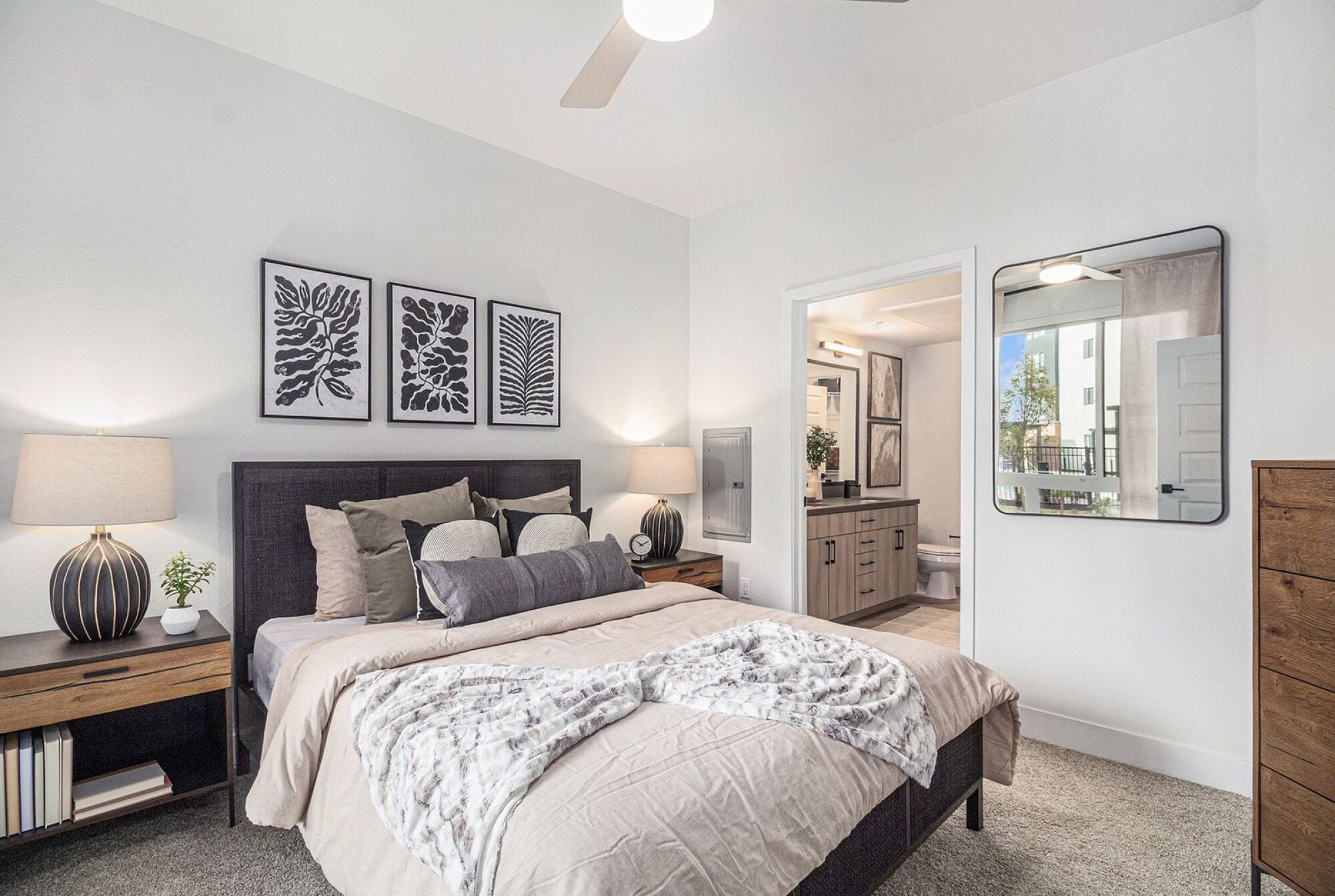 A modern bedroom in Solana Central Park with abstract black-and-white artwork above the bed, soft lighting, and an ensuite bathroom visible through an open door.