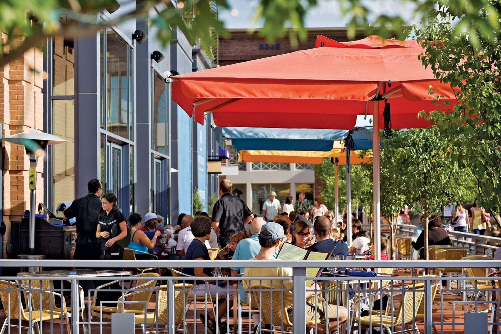 Outdoor restaurant seating area filled with customers seated under umbrellas