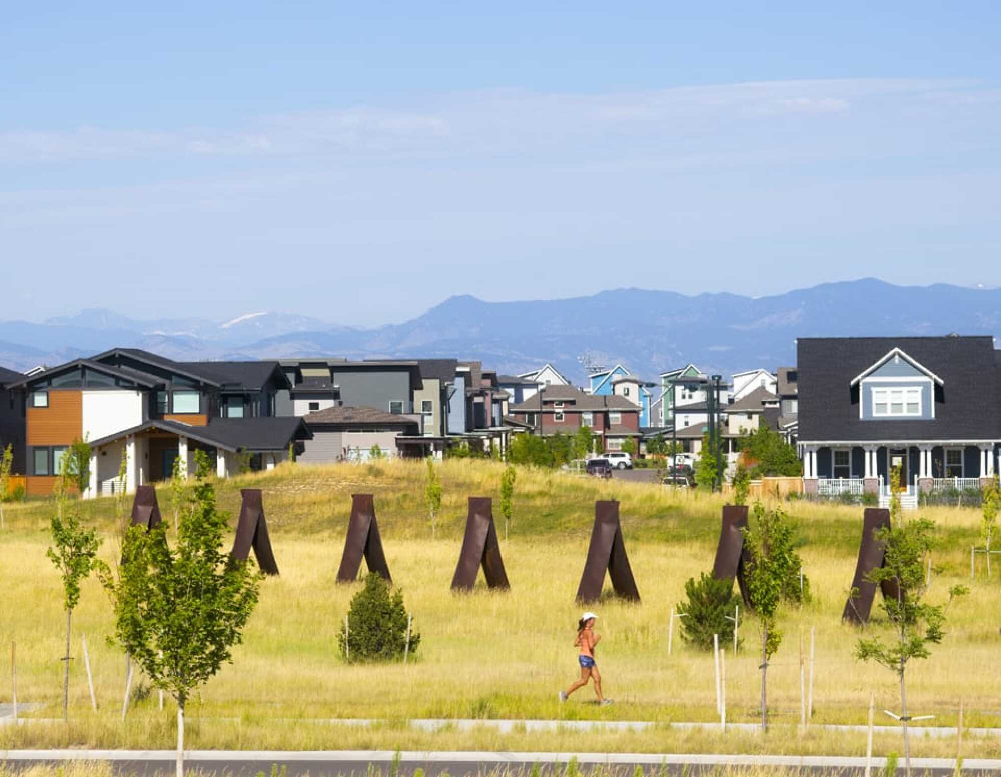 Running path alongside residential community with Rocky Mountains in background