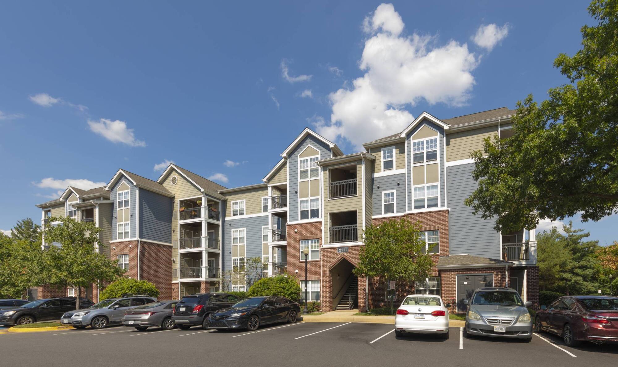 Milestone Apartments Outdoor patio with Adirondack chairs around a fire pit, surrounded by trees and apartment buildings.