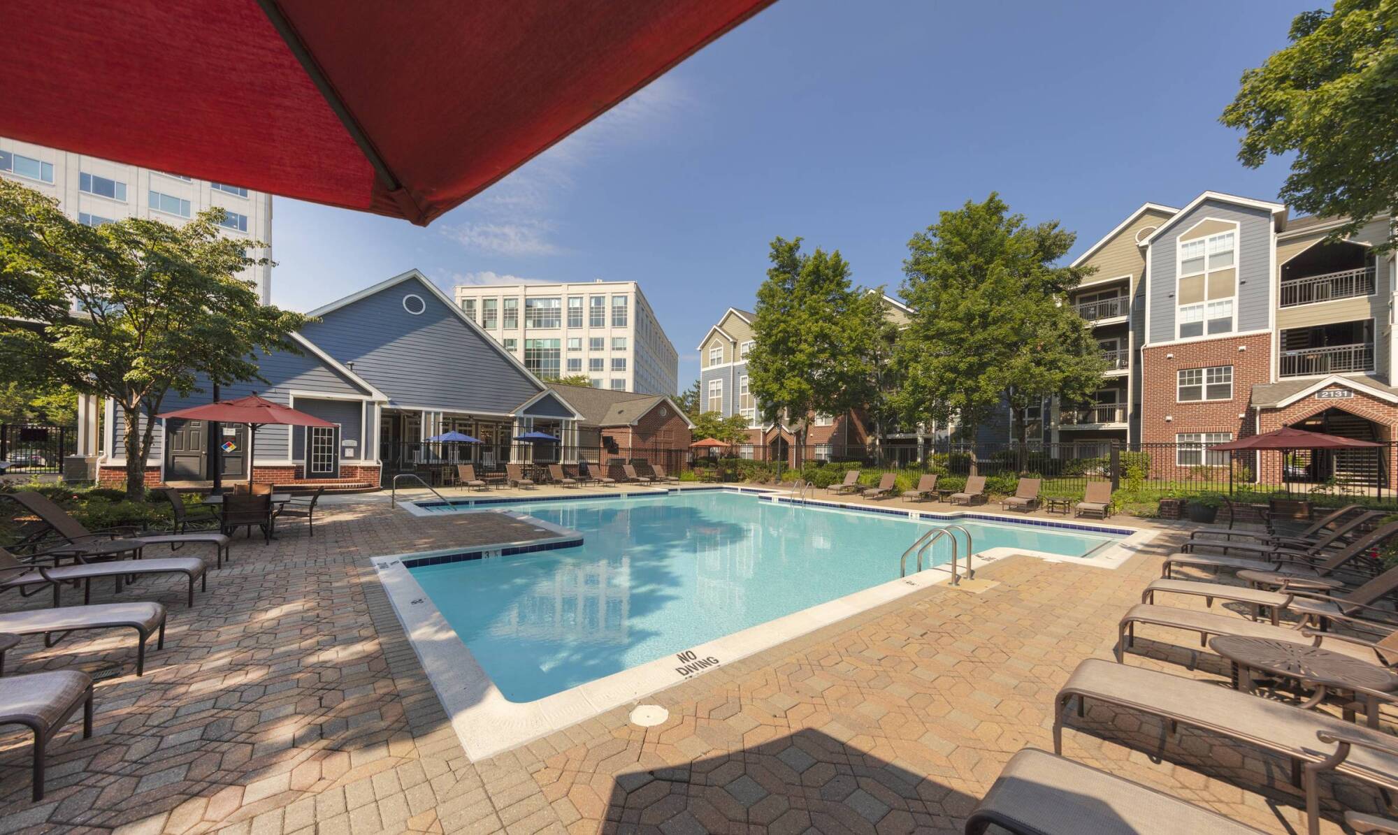 Milestone Apartments Outdoor patio with Adirondack chairs around a fire pit, surrounded by trees and apartment buildings.