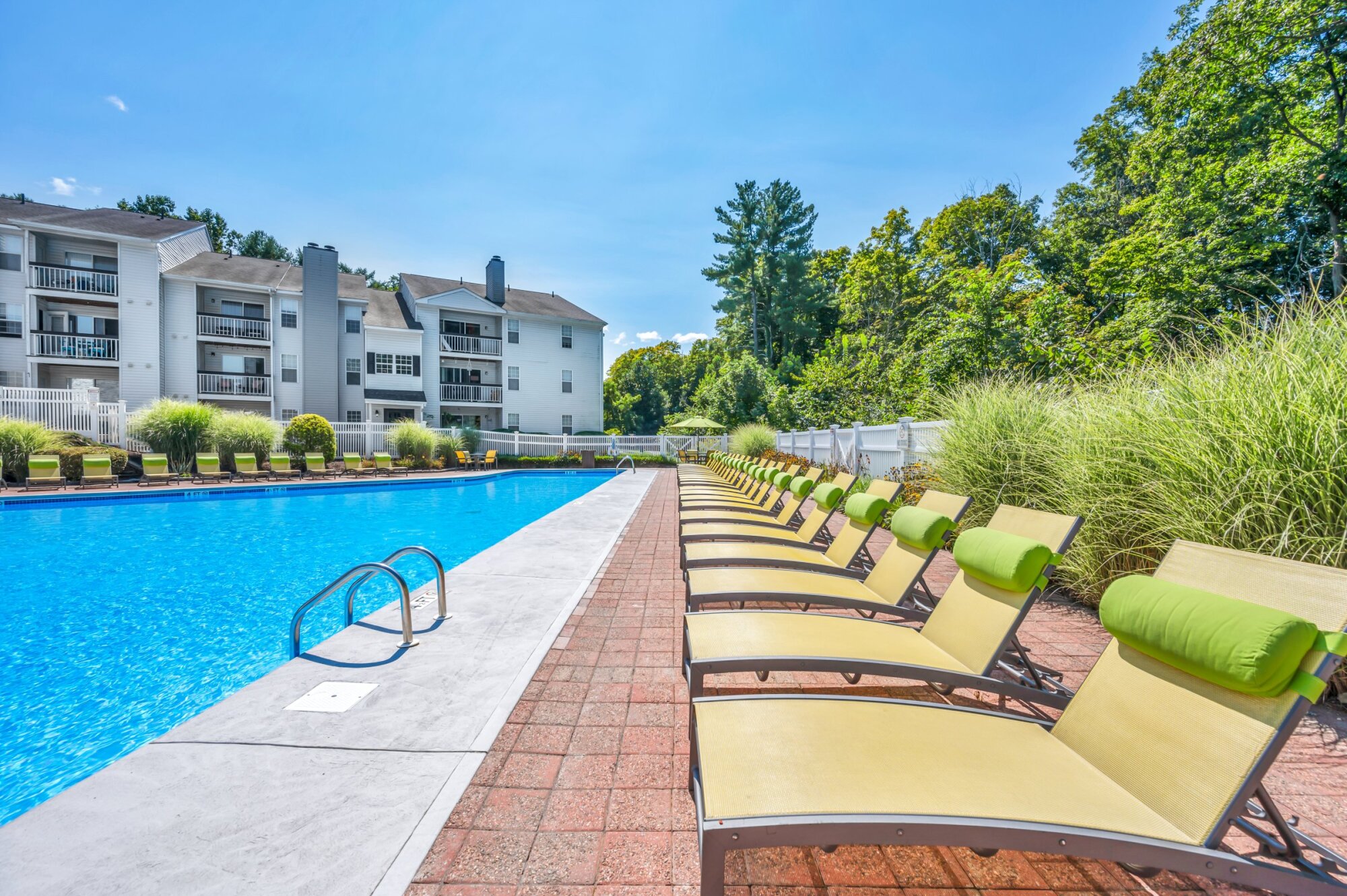 Milestone Apartments Outdoor patio with Adirondack chairs around a fire pit, surrounded by trees and apartment buildings.