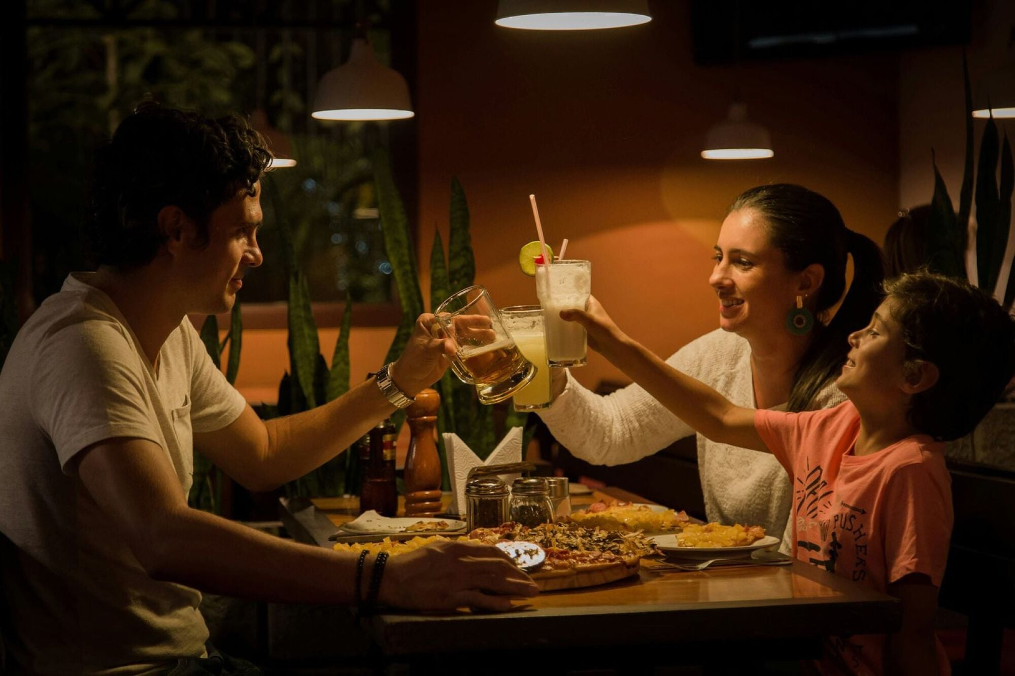 Friends raising glasses over a shared pizza at a neighborhood restaurant near Maple Run in Charlotte, NC.