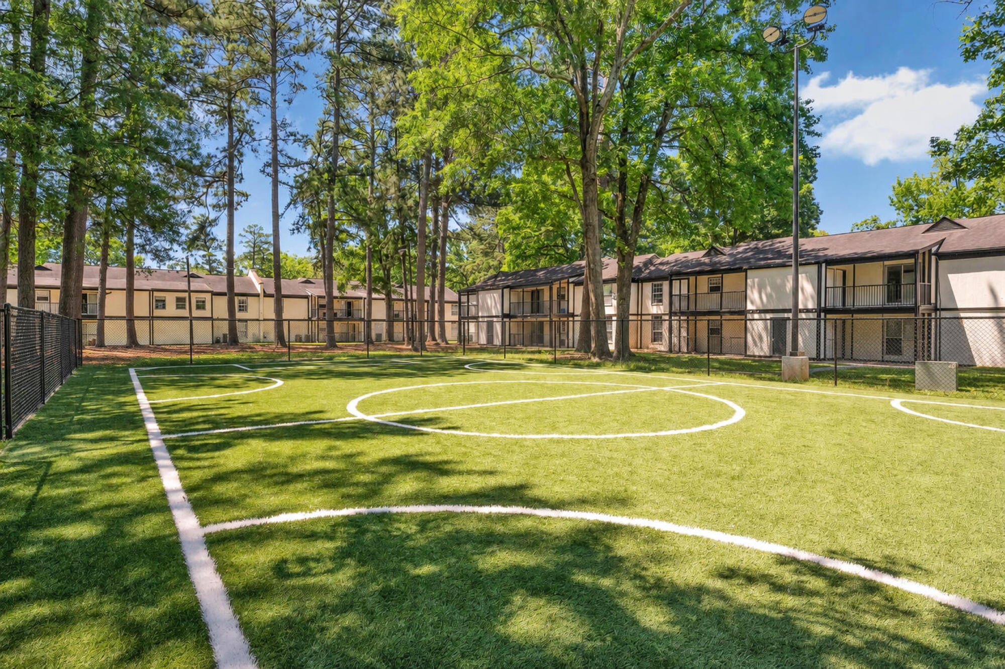 Fenced turf soccer field at Maple Run in Charlotte, NC, framed by mature trees for outdoor recreation and play.