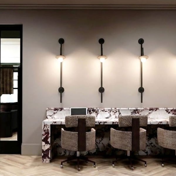 A long table with chairs and lights on the wall.