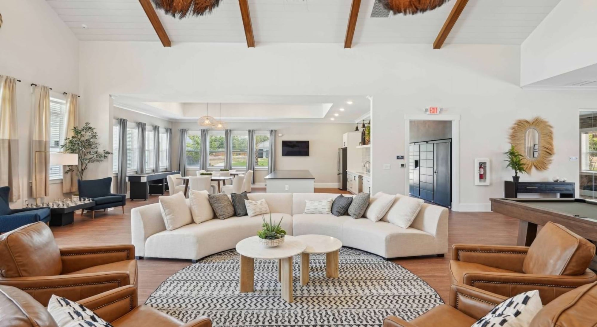 Modern living room with gray accent wall, cozy seating, wood table, sideboard, lamps, art, and patio doors letting in sunlight.