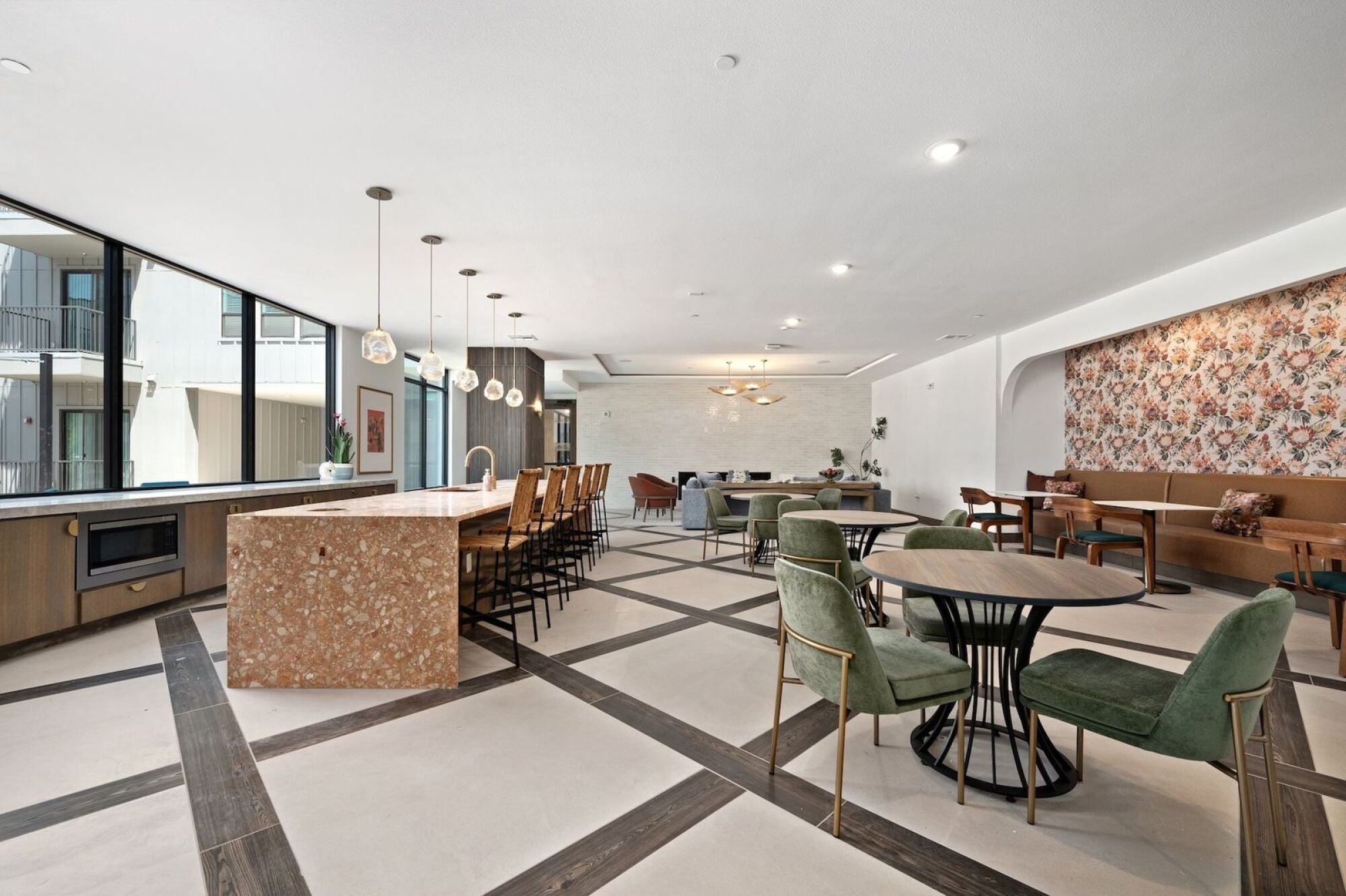 Wixby House clubroom in Austin, TX featuring a spacious kitchen, marble island, dining tables, lounge seating, and floral accent wallpaper.