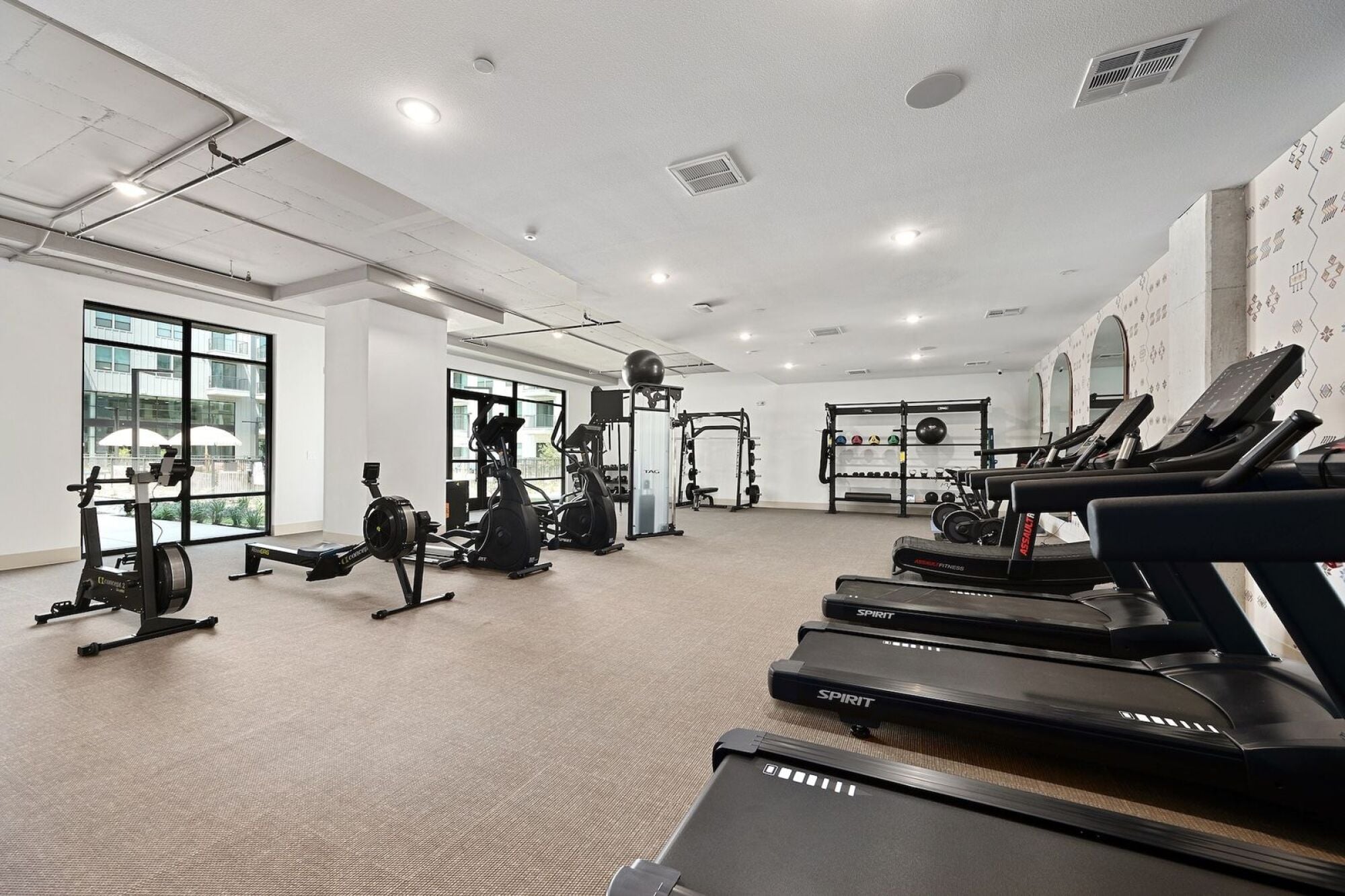 Wixby House fitness center in Austin, TX featuring treadmills, rowing machines, strength training equipment, and free weights.