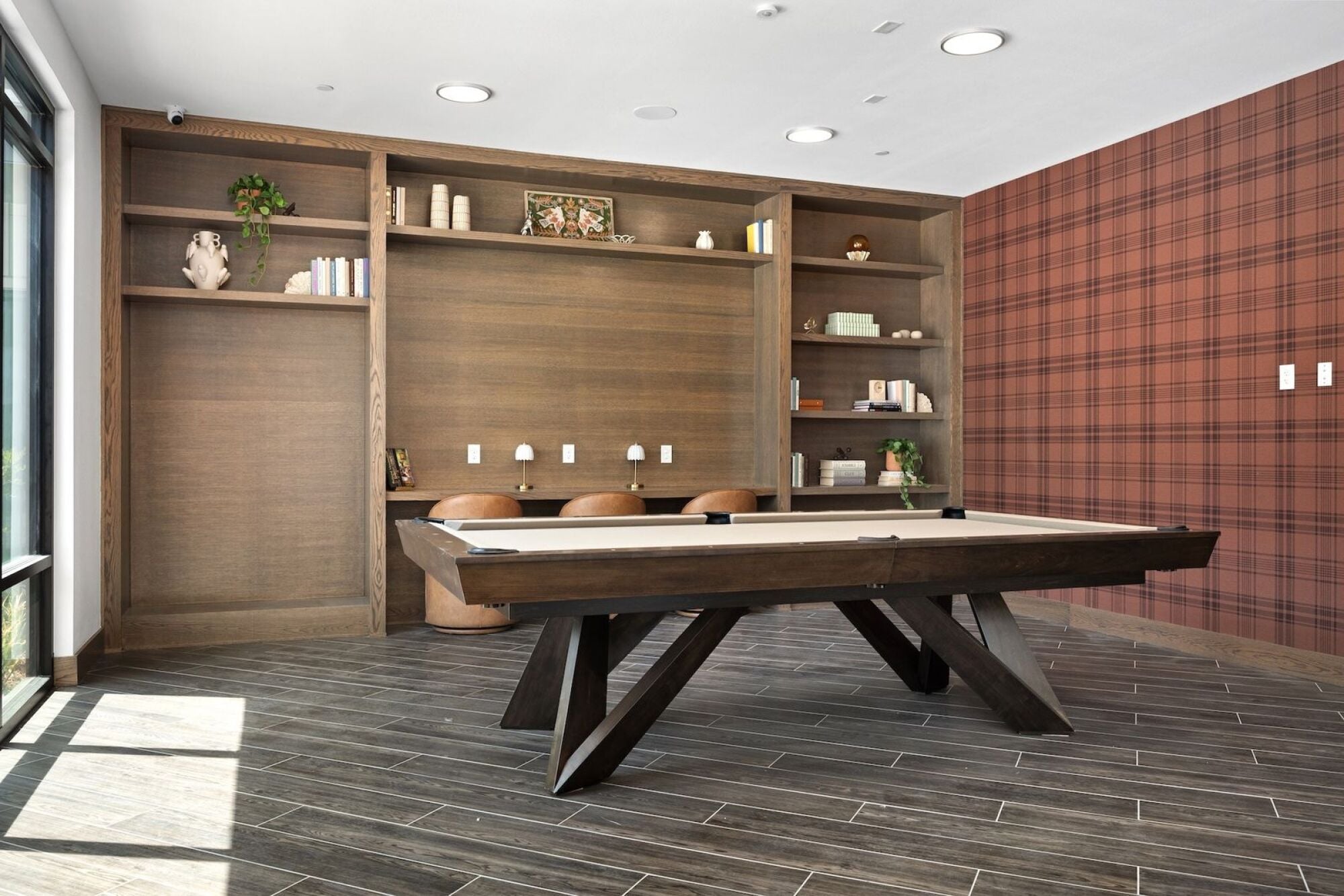 Wixby House game room in Austin, TX featuring a pool table, built-in wood shelving, comfortable seating, and patterned wallpaper.