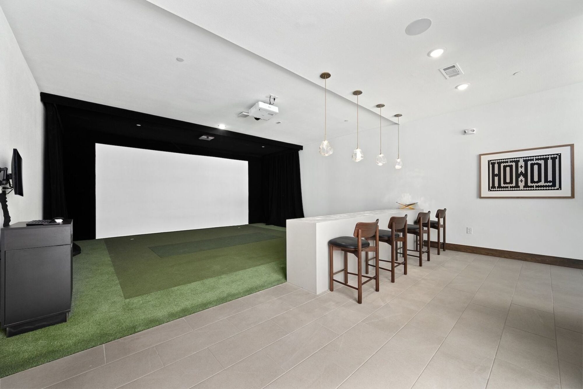 Wixby House golf simulator in Austin, TX featuring a large projection screen, golf hitting area, and bar seating.