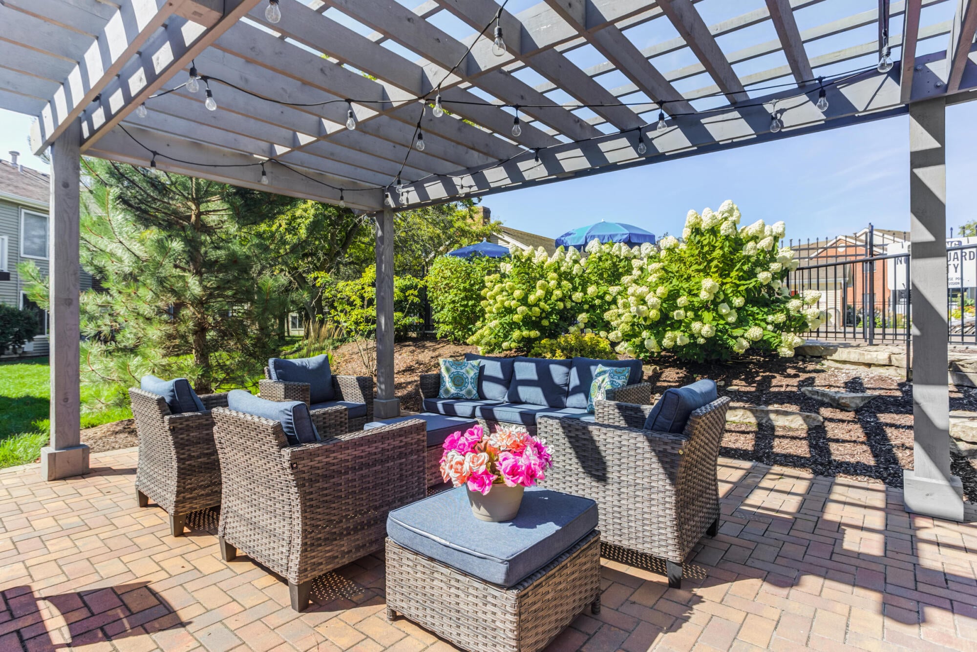 Covered pergola lounge with cushioned seating and string lights at Ashford at Geneva apartments in Geneva, IL
