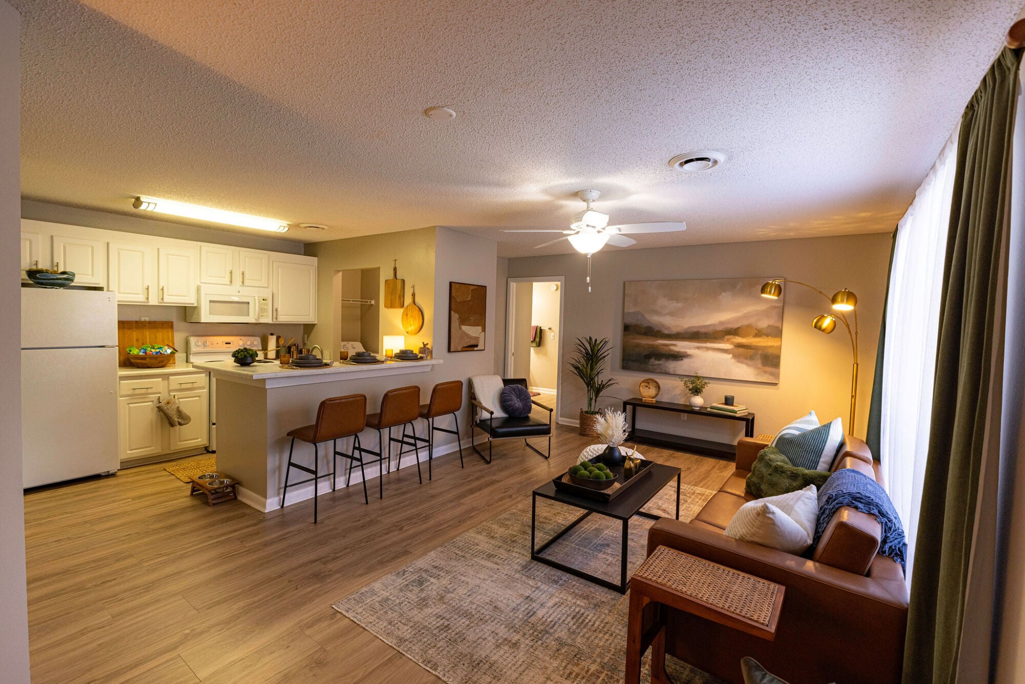 Open-concept living room and kitchen with breakfast bar seating in a Knox Row apartment in Knoxville, Tennessee.