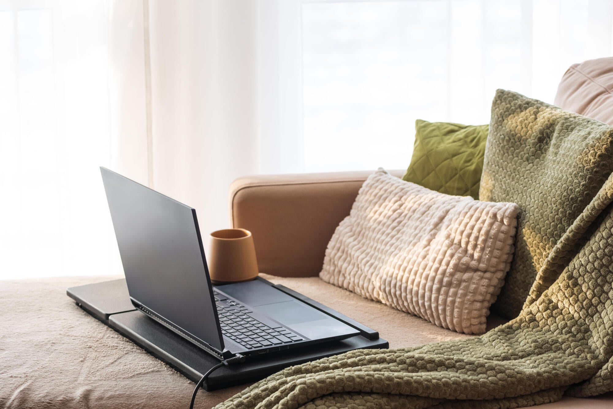 Laptop and a knit throw on the sofa in a comfortable apartment at Merit 38 in Fargo, ND