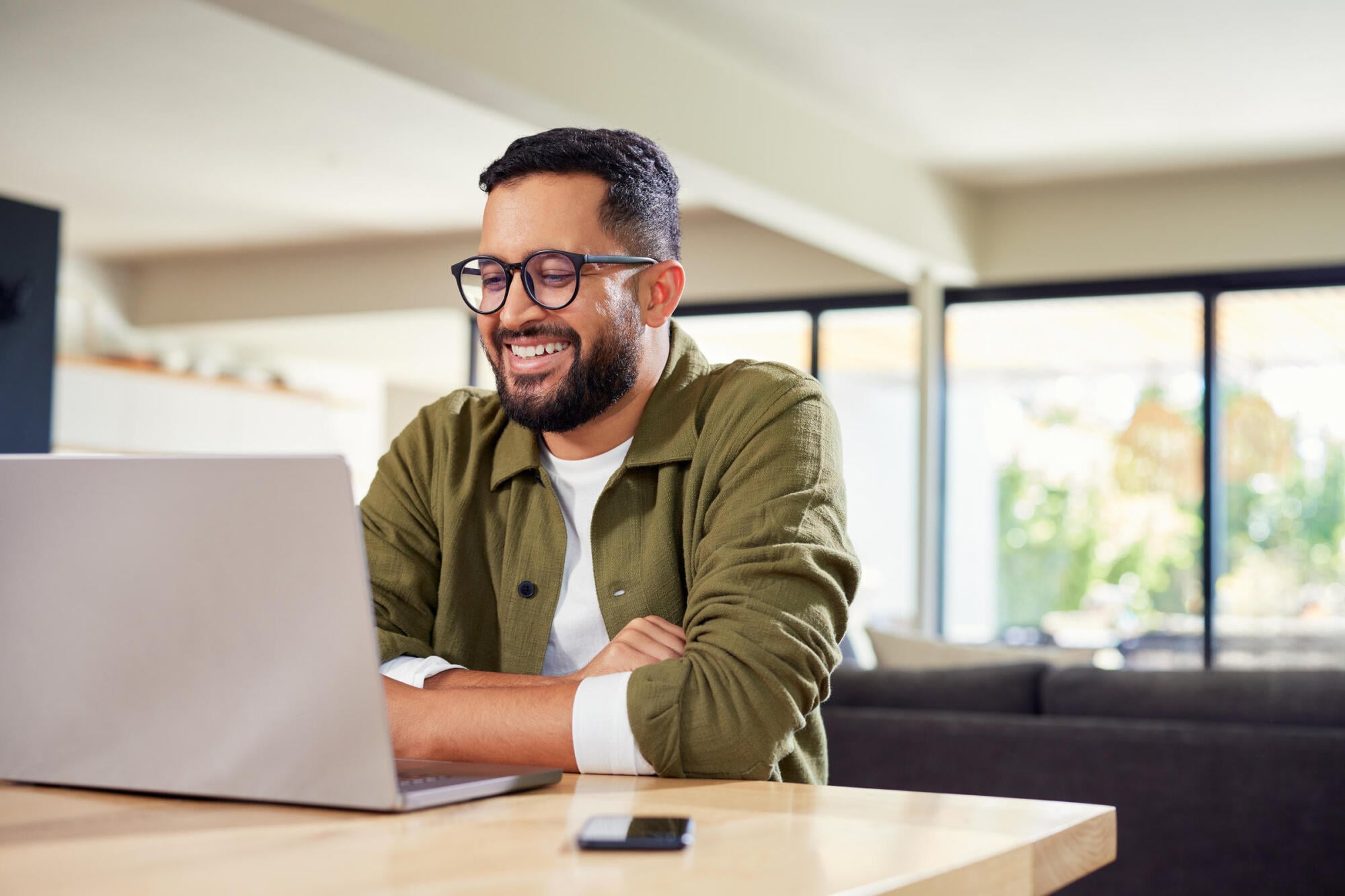 Resident working on a laptop beside a sunny window in an apartment at Merit 38 in Fargo, ND