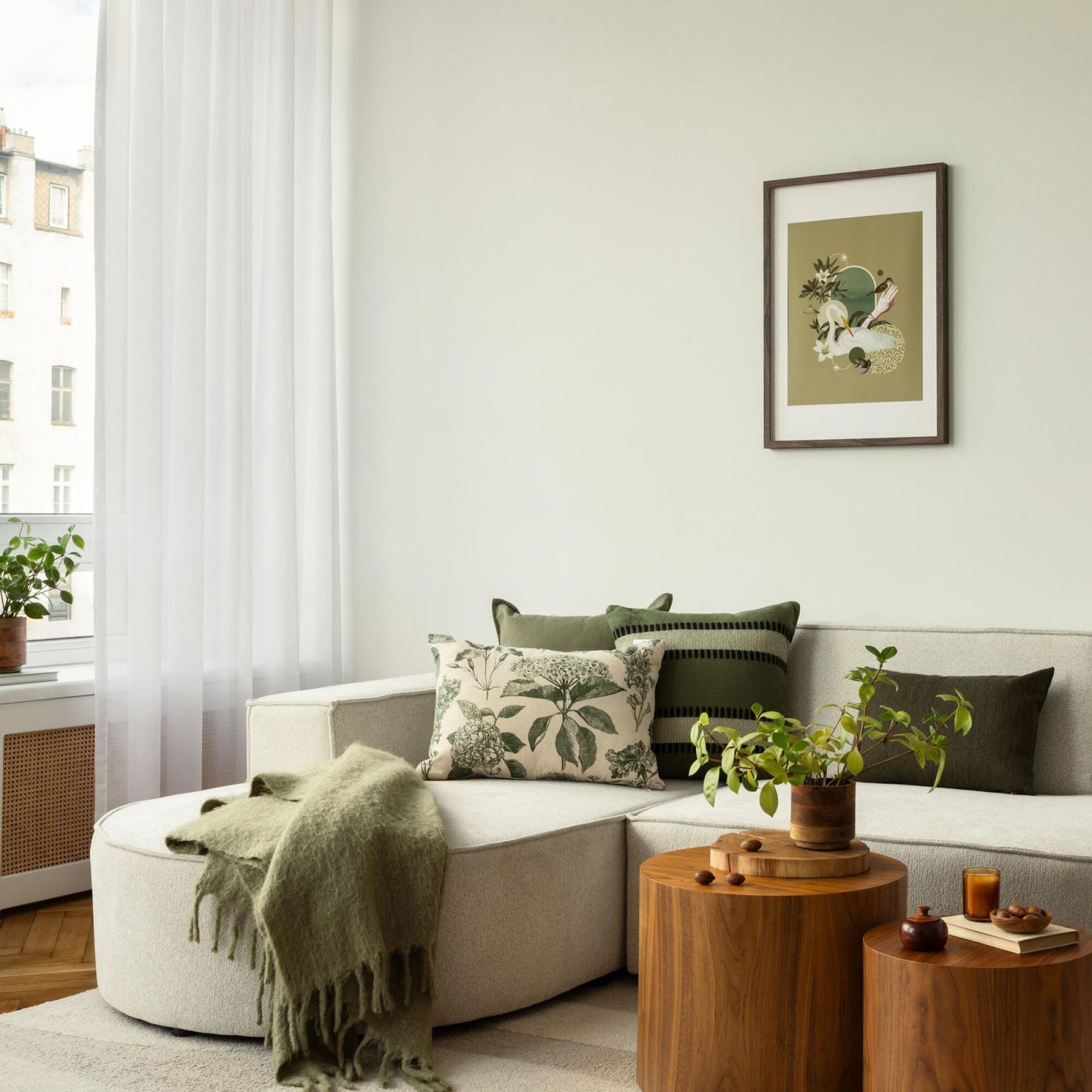 Light-filled apartment living room with green accent pillows and wood tables at Merit 38 in Fargo, ND