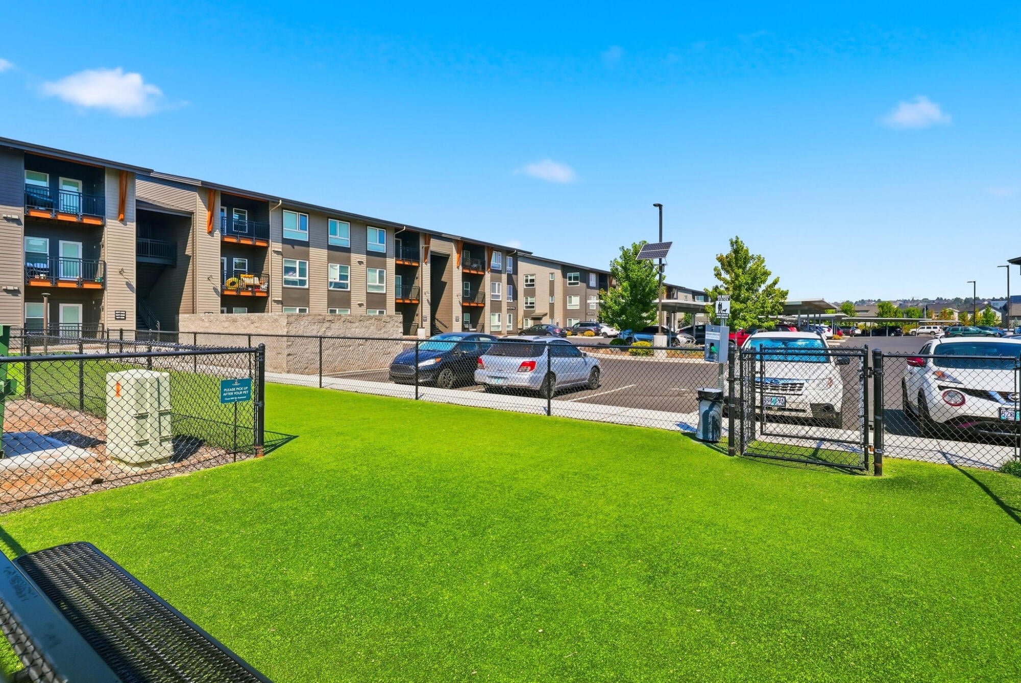 Fenced dog park with artificial turf beside the apartment buildings at Cypress in Redmond, Oregon.