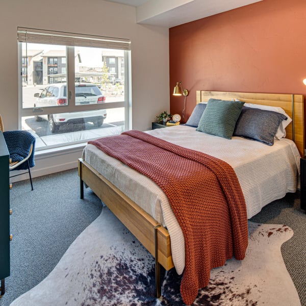 Furnished model bedroom with a warm terracotta accent wall at Cypress apartments in Redmond, Oregon.