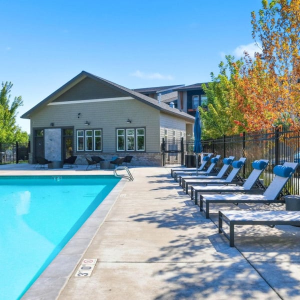Shaded pool deck with lounge chairs beside the clubhouse at Cypress in Redmond, Oregon.