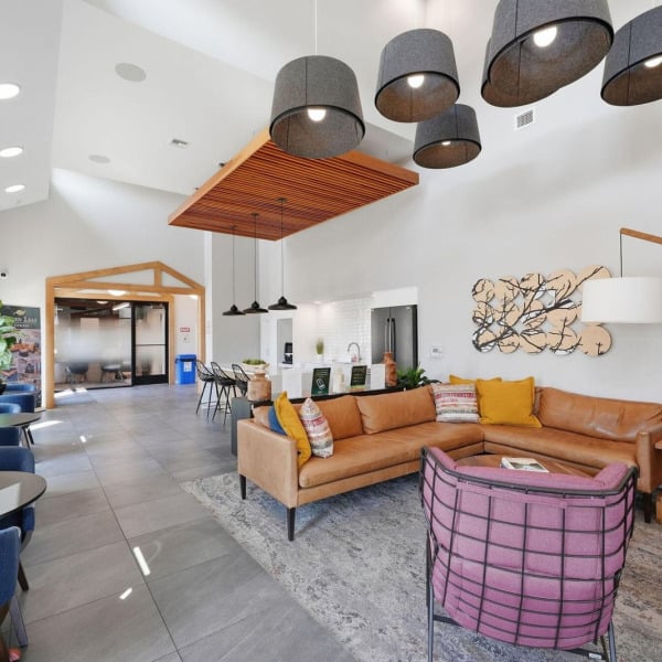 Resident lounge with sectional seating, felt pendants, and a wood slat ceiling at Cypress in Redmond, Oregon.