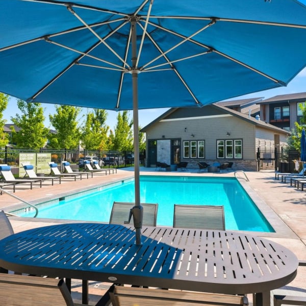 View of the pool and clubhouse from beneath a poolside umbrella at Cypress in Redmond, Oregon.