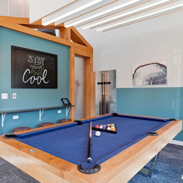 Blue-felt billiards table with a cue rack and chalkboard nook at Cypress in Redmond, Oregon.