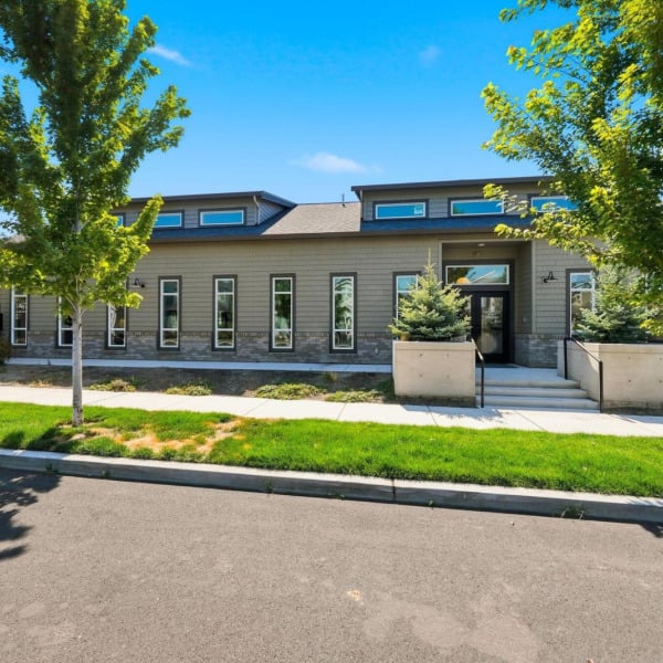 Street view of the Cypress clubhouse in Redmond, Oregon, framed by maple trees and high desert sky.