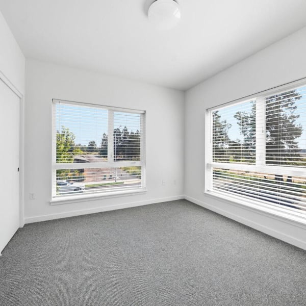 Bright bedroom with two oversized windows framing Central Oregon views at Cypress in Redmond, Oregon.